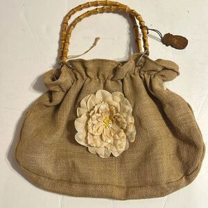 Tan purse made from burlap with beige flower and bamboo handles